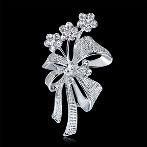 Broche nœud argentée avec strass et fleurs sur un fond noir élégant