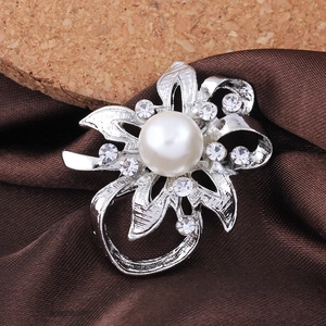 Close-up of silver floral brooch with large white pearl and sparkling rhinestones