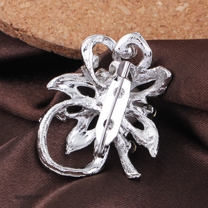 Back view of silver flower brooch with pin clasp on brown satin and cork background