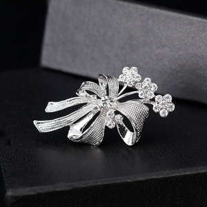Broche nœud argentée avec strass étincelants et détails floraux sur cuir noir texturé