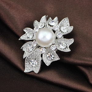 Broche fleur argentée avec perle blanche et cristaux brillants sur fond de soie