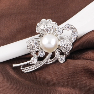 Vue macro détaillée d'une broche fleur argentée avec perle blanche et strass étincelants