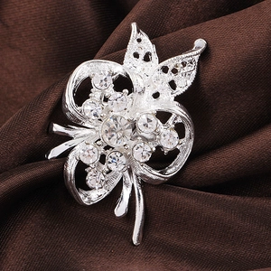 Vue macro d'une broche florale argentée avec strass scintillants sur satin noir