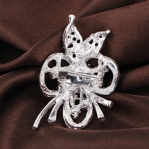 Broche nœud papillon ajourée en argent avec épingle de sûreté sur fond en satin brun