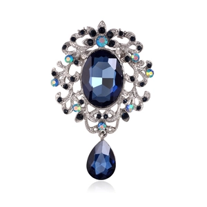 Vintage crystal brooch with blue oval gemstone and teardrop pendant on white background