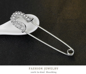 Close-up of vintage silver pin brooch with pavé rhinestones on white spoon