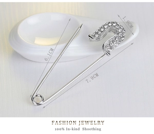 Macro detail of silver alloy brooch pin featuring white round rhinestone pave settings