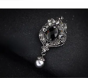 Detail of vintage silver brooch featuring a black faceted gemstone and a grey pearl drop