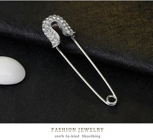 Detailed macro view of a silver safety pin brooch with sparkling white rhinestones