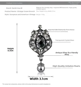 Macro detail of crown brooch with grey crystal and hanging faux pearl charm
