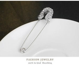 Macro detail of a silver safety pin brooch with sparkling rhinestones on ceramic