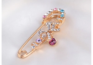 Vue rapprochée d'une broche nœud dorée avec strass colorés et pendentif rouge