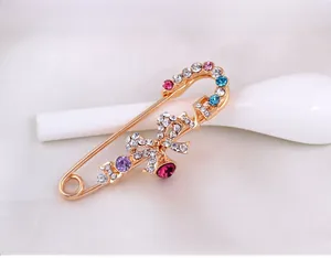 Gros plan détaillé d'une broche LOVE dorée avec strass multicolores et gemme rose en goutte