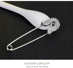Macro shot of silver safety pin brooch with sparkling rhinestones and metal texture