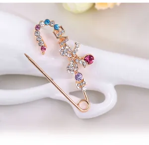 Détail d'une broche nœud avec strass colorés présentée sur un support de main en céramique