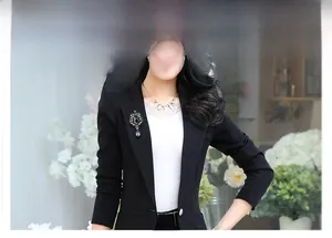 Close-up of a vintage crystal brooch with grey pearl drop on a black suit blazer