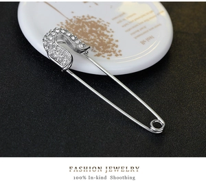 Macro shot of silver alloy safety pin brooch with sparkling rhinestone pavé head detail