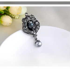 Detailed macro of vintage silver brooch with black gemstone and hanging grey pearl bead