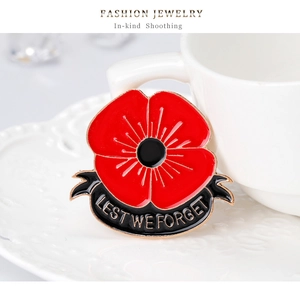 Detail of red enamel poppy brooch featuring Lest We Forget text on white ceramic