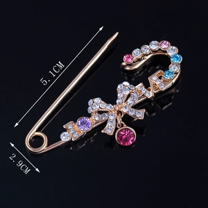 Broche épingle dorée avec lettrage LOVE et strass colorés sur fond noir brillant