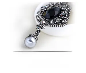 Detail of vintage oval black gemstone brooch with white crystals and grey pearl drop