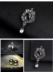 Macro view of vintage silver hollow brooch with black gemstone and grey pearl drop