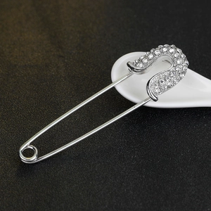 Vintage silver paperclip brooch with crystal rhinestones on a minimalist dark background