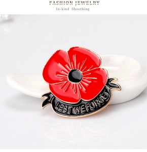 Detail of red enamel poppy brooch with Lest We Forget gold engraving on black ribbon