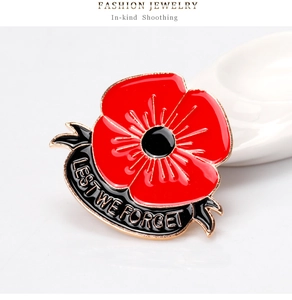 Detail of red enamel poppy brooch with crystal accents and Lest We Forget engraving