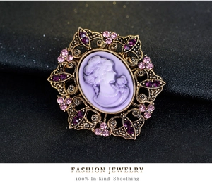 Macro shot of vintage cameo brooch with purple relief and crystals on black fabric