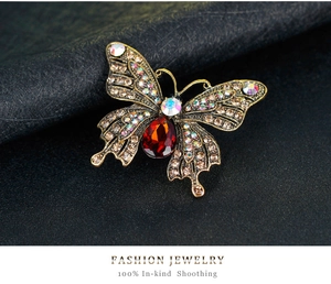 Macro detail of butterfly brooch featuring champagne rhinestones and red teardrop crystal