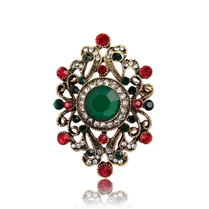 Broche vintage dorado con una gran gema verde y brillantes diamantes de imitación