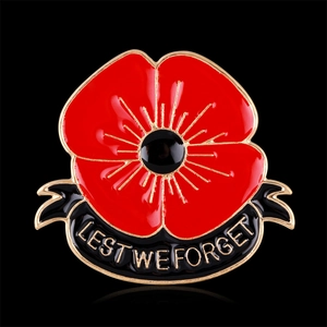 Poppy flower enamel pin with Lest We Forget gold text and red rhinestones on black background