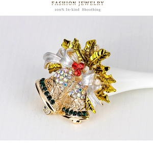 Dettaglio macro della spilla a campana di Natale con strass colorati e oro lucido