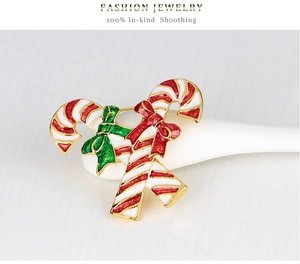 Close-up of Christmas candy cane brooch with red and green bows on a white surface