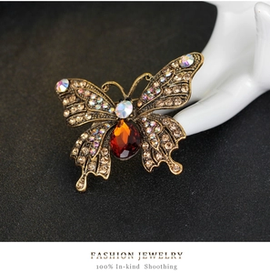 Detailed macro view of vintage gold butterfly brooch featuring champagne rhinestones and red gem