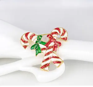 Detail of candy cane Christmas brooch with red and green enamel bows on hand model