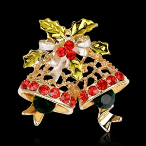Christmas gold bell brooch with green holly leaves and red rhinestone accents on black background