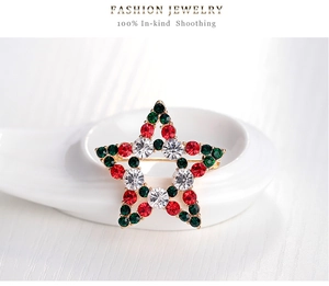Detail of Christmas star brooch with red and green crystals on white ceramic plate