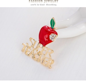 Makroaufnahme der roten Apfelbrosche mit Super Teacher Schriftzug und Strass