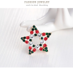 Close-up of Christmas star brooch with red and green rhinestones on golden base