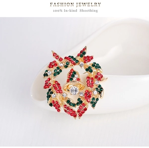 Close-up of Christmas wreath brooch with red and green rhinestones and a gold bell