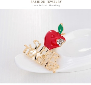 Nahaufnahme der roten Apfelbrosche mit Glitzersteinen und goldenem Super Teacher Schriftzug