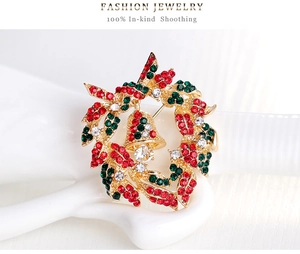 Detail of Christmas wreath brooch with red and green rhinestones and a small bell