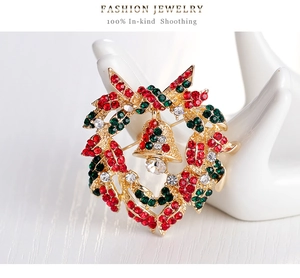 Macro detail of Christmas wreath brooch with red and green rhinestones on gold base