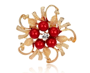 Close-up of vintage flower brooch with golden scrollwork, red pearls and center crystal
