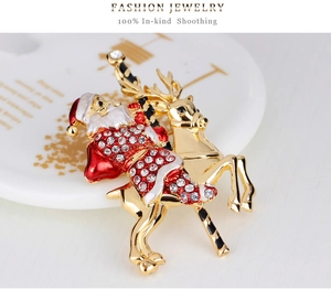 Detailed close-up of a Christmas brooch with Santa on reindeer in gold and enamel