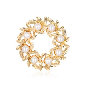 Close-up of golden wreath brooch with eight white pearls and intricate leaf textures