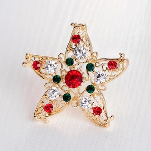 Goldene Sternbrosche mit roten, grünen und weißen Kristallen auf hellem Holzhintergrund