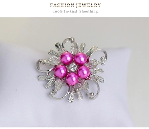 Macro detail of alloy flower brooch with pink pearls and cubic zirconia on a white pillow